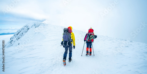 Couple of tourists trekking winter mountain top covered with snow