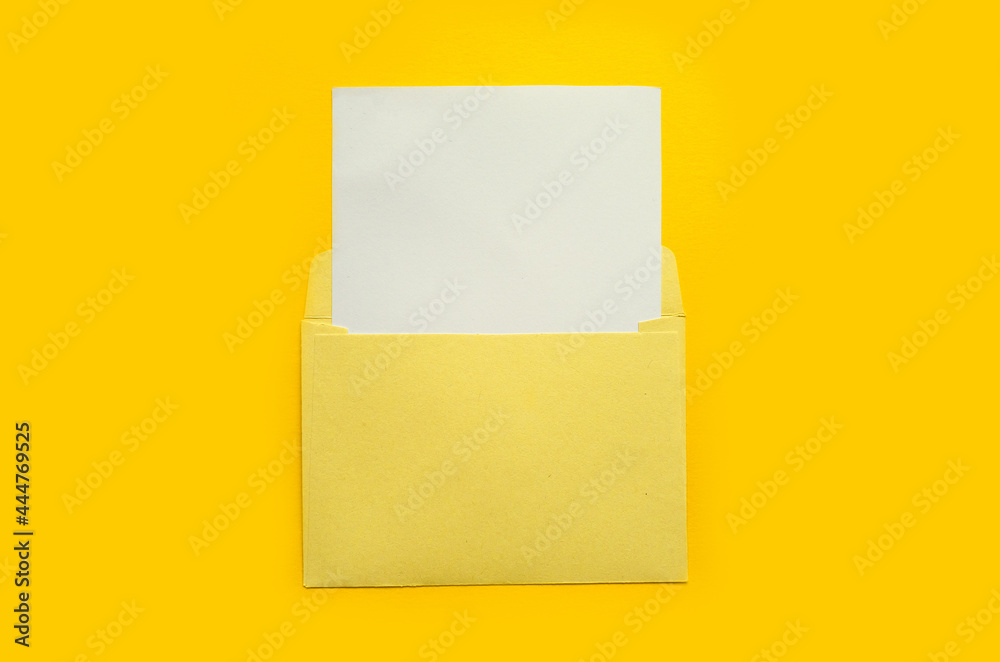 Yellow envelope with a white mockup sheet on yellow background Yellow envelope with a white mockup sheet on yellow background