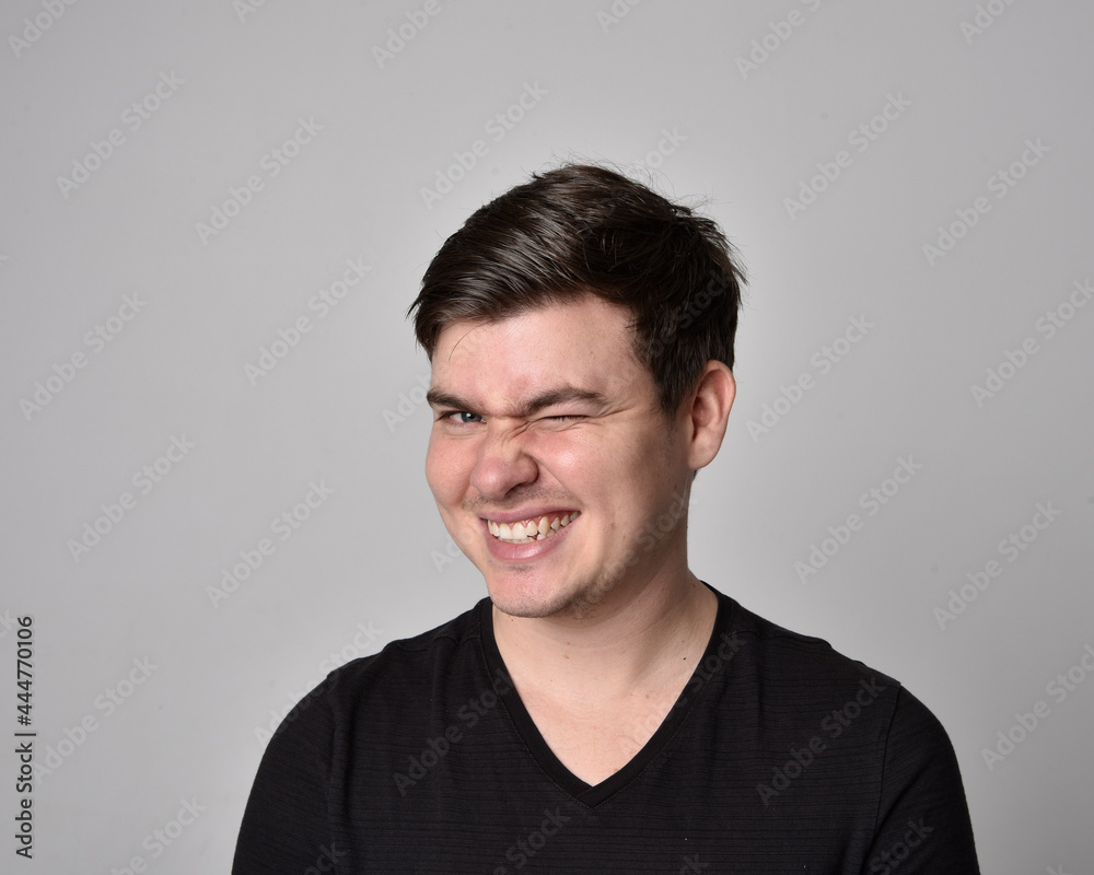 Fototapeta premium Close up head and shoulders portrait of a brunette. young man with a variety of expressive facial expressions. Isolated on a light grey studio background.
