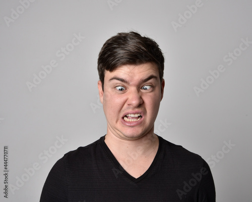 Close up head and shoulders portrait of a brunette. young man with a variety of expressive facial expressions. Isolated on a light grey studio background.