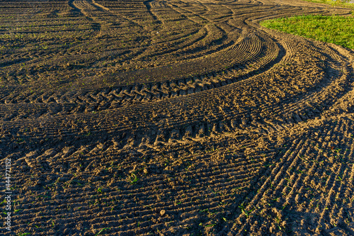 View of a plowed field with traces and furrows of a tractor meandering through the arable soil