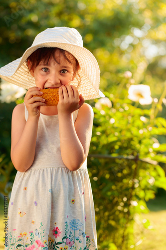 Happy little girl eating corn on the cob.