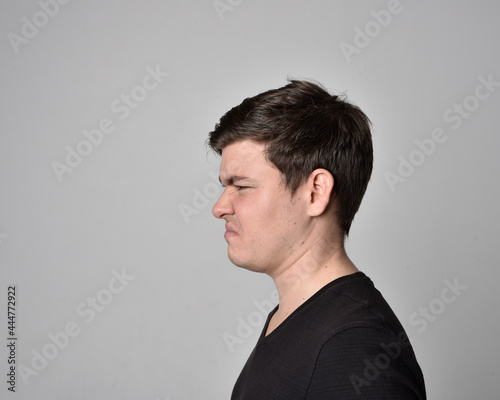 Close up head and shoulders portrait of a brunette. young man with a variety of expressive facial expressions. Isolated on a light grey studio background.