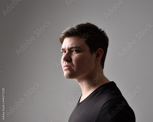 Close up head and shoulders portrait of a brunette. young man with a variety of expressive facial expressions. Isolated on a light grey studio background.