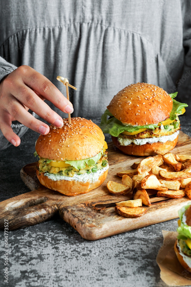 Vegan lentil burgers in the womam hands, with salad and yogurt sauce on a white background. Plant based food concept. Vegan lentil burgers in the womam hands, with salad and yogurt sauce on a white background. Plant based food concept.
