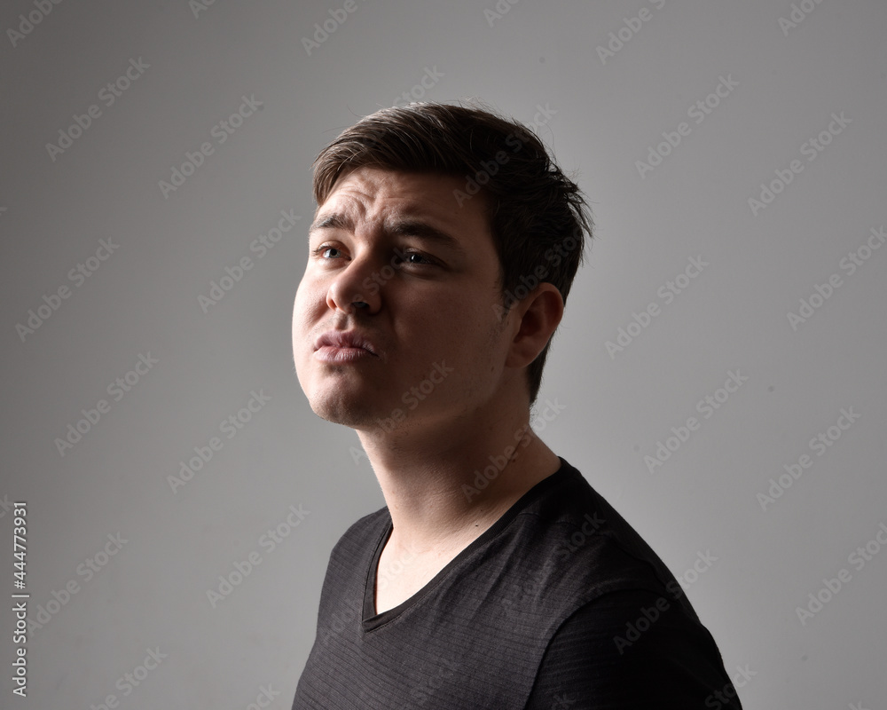 Close up head and shoulders portrait of a brunette. young man with a variety of expressive facial expressions. Isolated on a light grey studio background. Close up head and shoulders portrait of a brunette. young man with a variety of expressive facial expressions. Isolated on a light grey studio background.