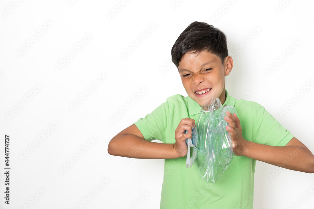 A boy makes gestures of strength while crushing a plastic bottle with his hands to recycle it. Recycling concept for children A boy makes gestures of strength while crushing a plastic bottle with his hands to recycle it. Recycling concept for children