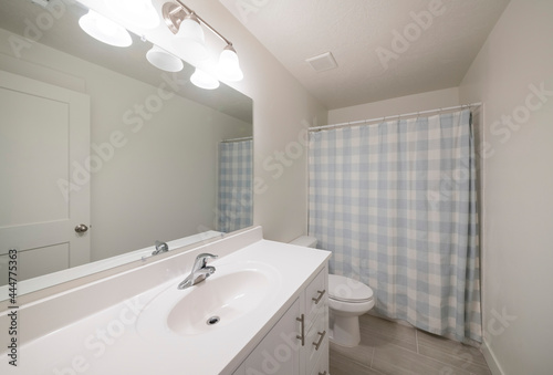 Clean bathroom with white vanity sink and closed checkered shower curtain