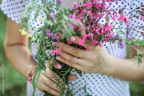 a girl in a white light dress holds a bouquet of wild flowers in her hands. depersonalized photo  midsection  copy space  selective focus