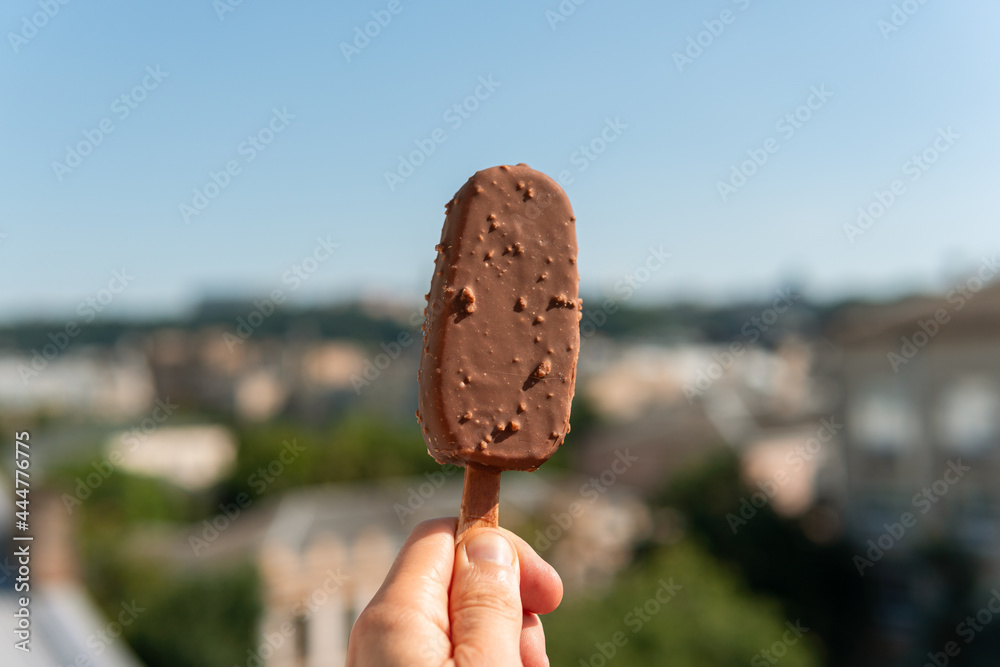 Obraz premium Tasty black ice cream with caramel pieces on a stick in hand