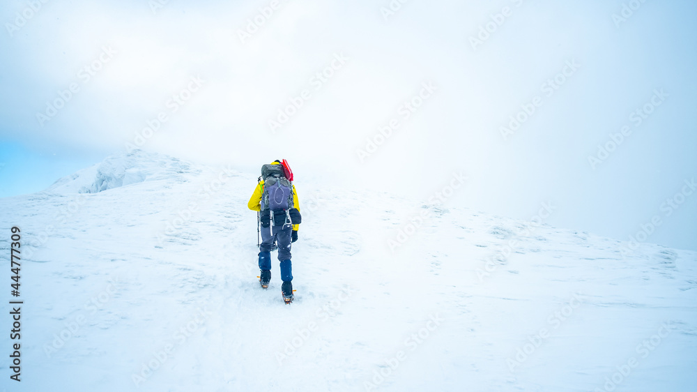 Lonely tourist trekking winter mountain top covered with snow