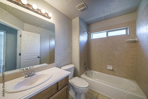 Bathroom interior with single vanity sink and bathtub shower unit with ceramic tiles surround
