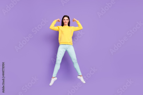 Full length body size view of attractive cheerful girl jumping showing strong muscles isolated over violet purple color background