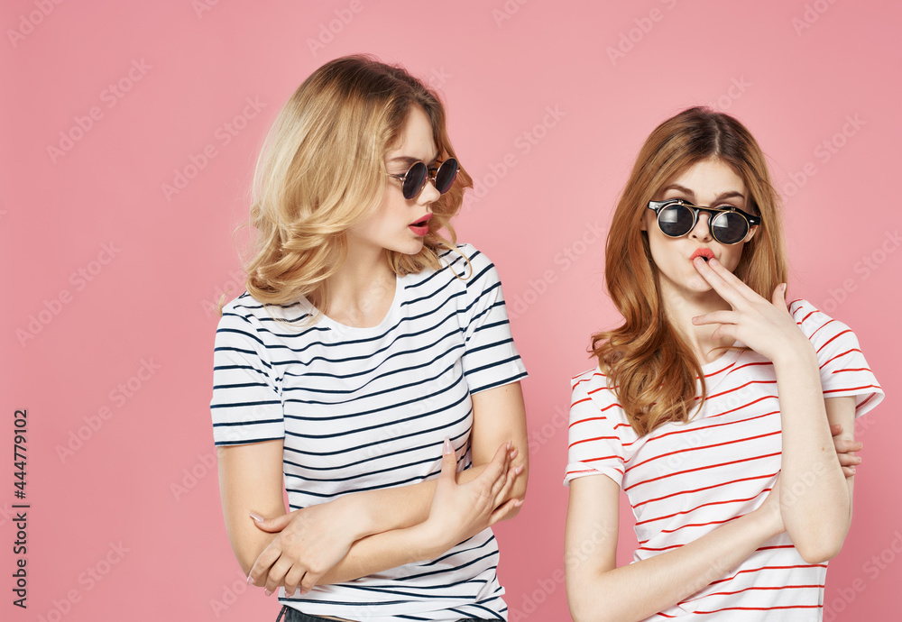 two girlfriends in sunglasses in a striped t-shirt pink background communication two girlfriends in sunglasses in a striped t-shirt pink background communication