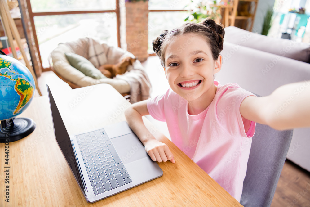 Photo of sweet shiny schoolgirl dressed t-shirt sitting table recording video doing homework modern gadget indoors room home house Photo of sweet shiny schoolgirl dressed t-shirt sitting table recording video doing homework modern gadget indoors room home house