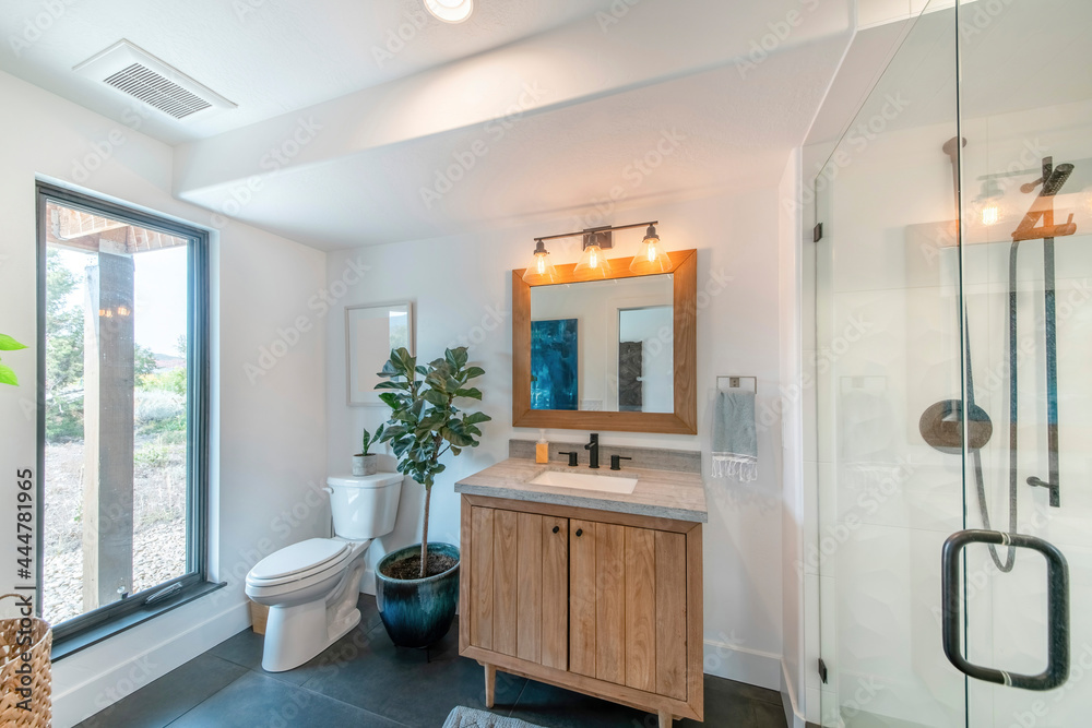 Boho bathroom design with large window near the toilet bowl with plants on top and side Boho bathroom design with large window near the toilet bowl with plants on top and side