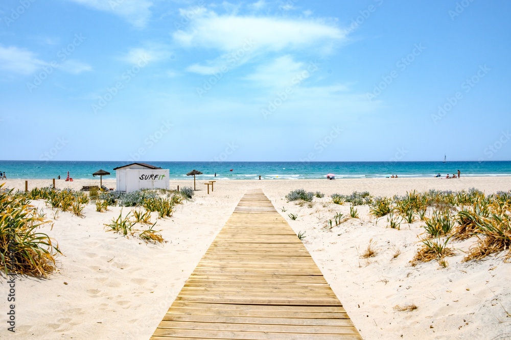 Pasarela de madera natural en playa sobre la arena camino hacia el mar