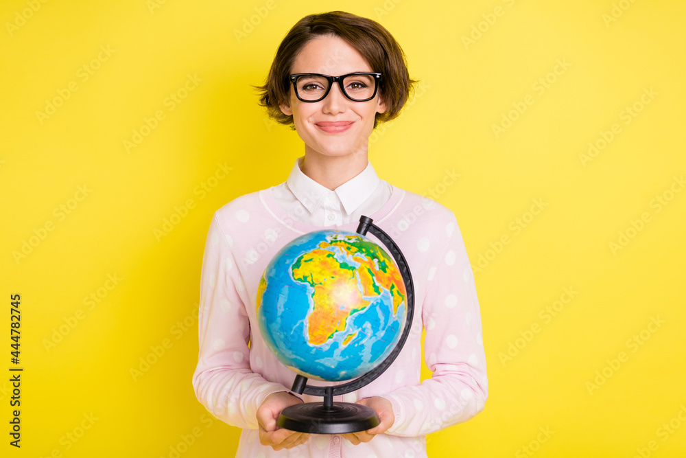 Photo portrait female geek keeping globe at school smiling isolated bright yellow color background Photo portrait female geek keeping globe at school smiling isolated bright yellow color background
