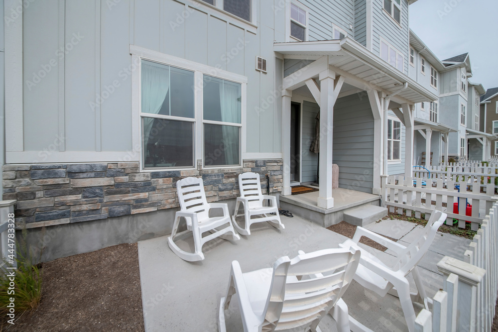 Patio in front of a townhouse with wooden white fence and rocking chairs