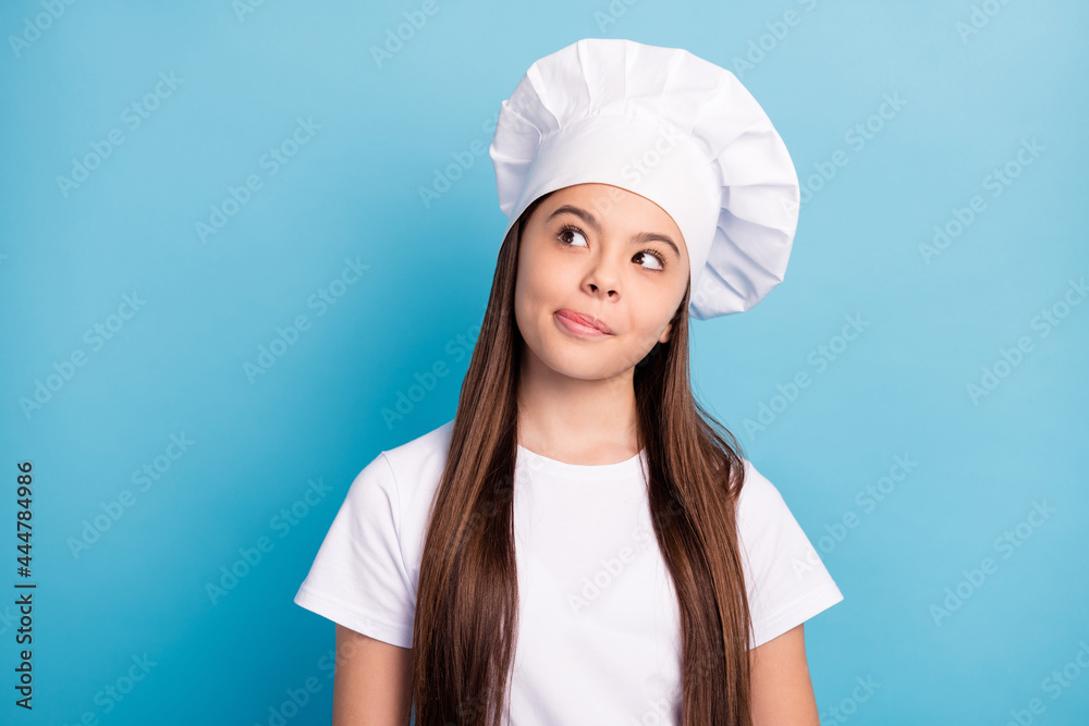 Photo of dreamy happy little girl cook look empty space lick lips imagine good meal isolated on blue color background