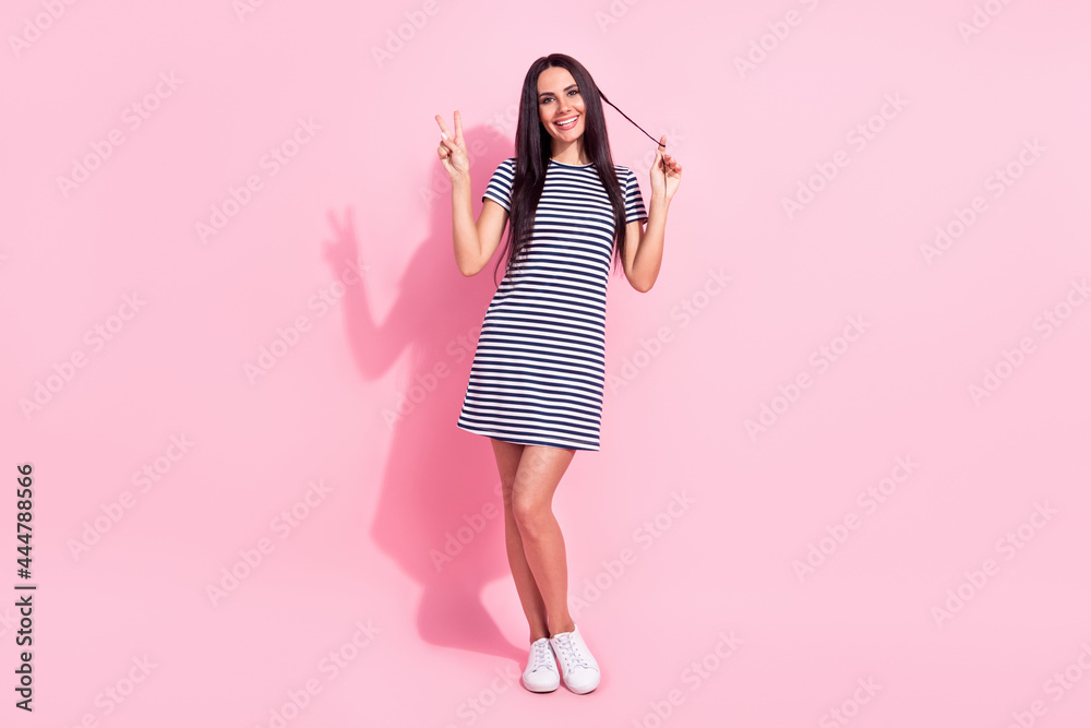 Full length body size photo of funky model showing v-sign gesture smiling isolated on pastel pink color background Full length body size photo of funky model showing v-sign gesture smiling isolated on pastel pink color background