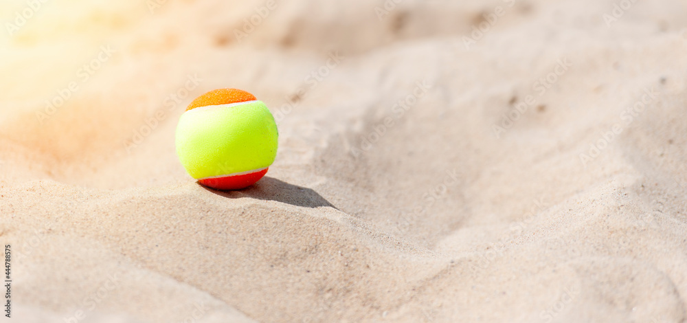 Tennis ball on the sand at the beach close up. Professional sport concept