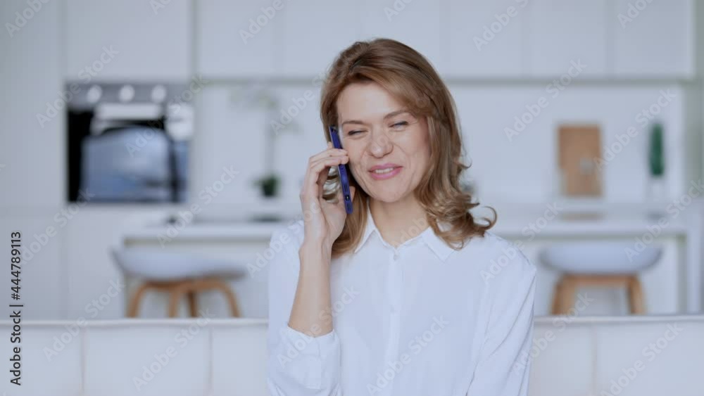 adult woman talking by mobile sitting in living room with white interior friendly blonde talking with cheerful smile adult woman talking by mobile sitting in living room with white interior friendly blonde talking with cheerful smile