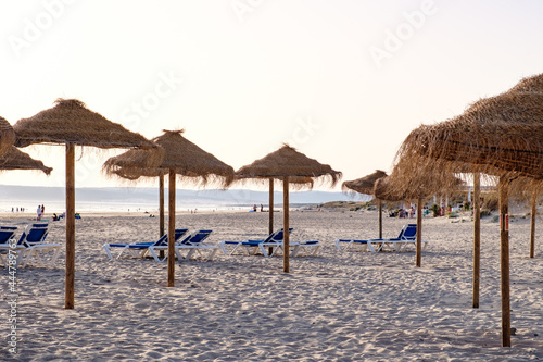 Playa con zona de sombrillas prefabricadas de madera y paja con diseño tropical