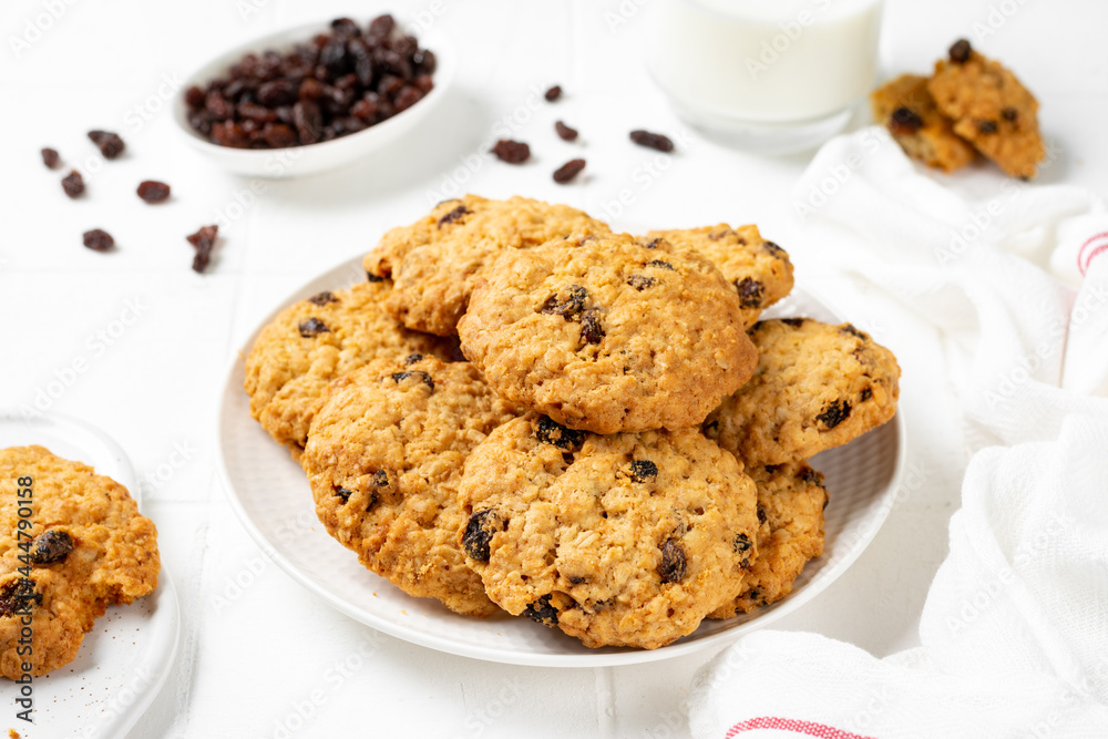 Homemade oatmeal cookies with raisins in a white plate on a light background closeup Homemade oatmeal cookies with raisins in a white plate on a light background closeup