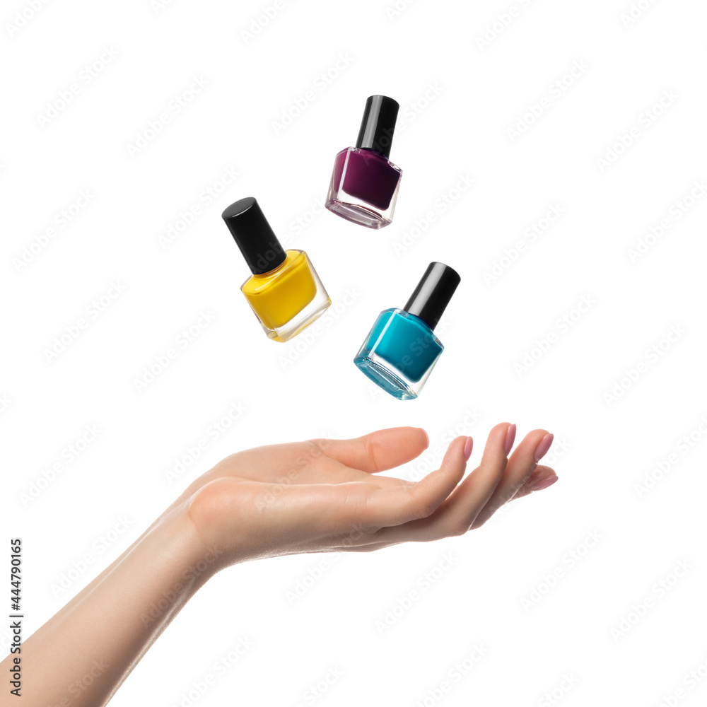 Nail polish bottles levitate, flying over a woman's hand Nail polish bottles levitate, flying over a woman's hand