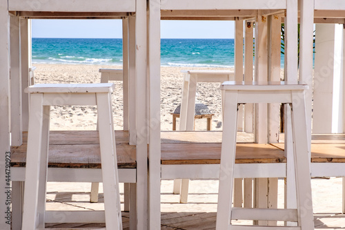 Taburetes alto de color blanco en exterior de restaurante en playa en dia de verano junto al mar