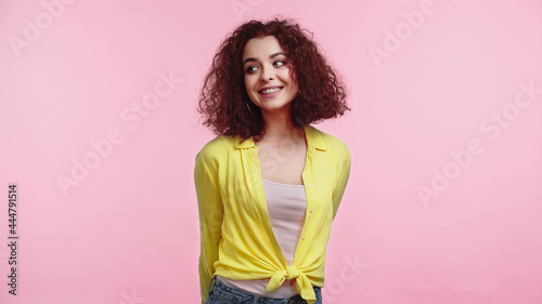 positive young woman in yellow shirt isolated on pink