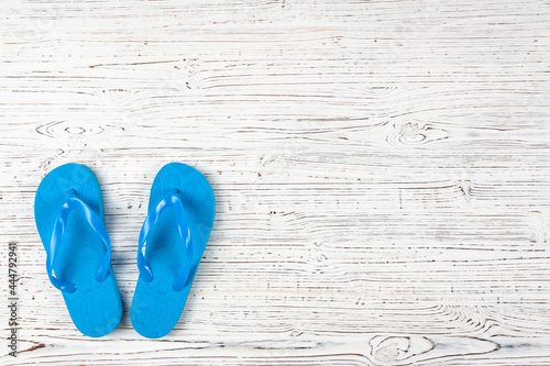 blue rubber flip-flops on a white wooden background, view from above, place under the text