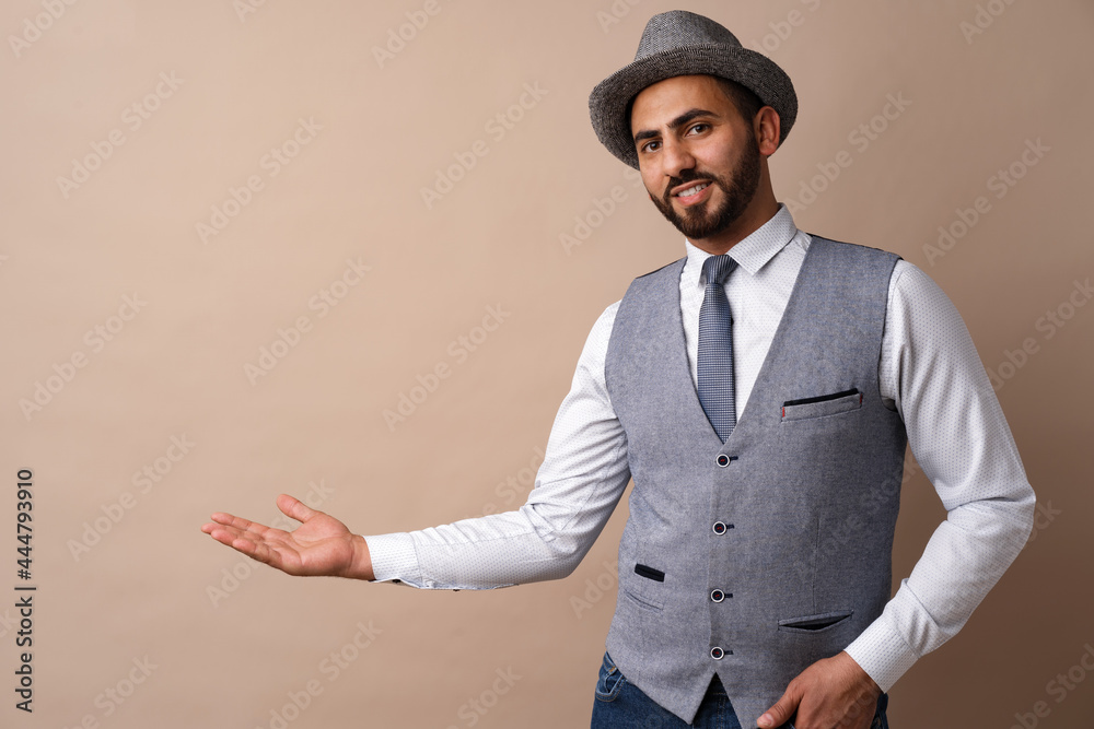 Young handsome arab man over beige background pointing to copy space and smiling Young handsome arab man over beige background pointing to copy space and smiling