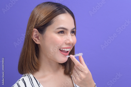 Young smiling woman holding invisalign braces in studio  dental healthcare and Orthodontic concept..
