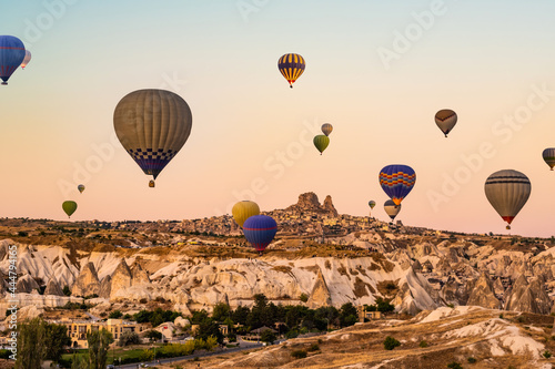 Colorful hot air balloons flying over beautiful valley in Cappadocia, Turkey on beautiful sunset sky