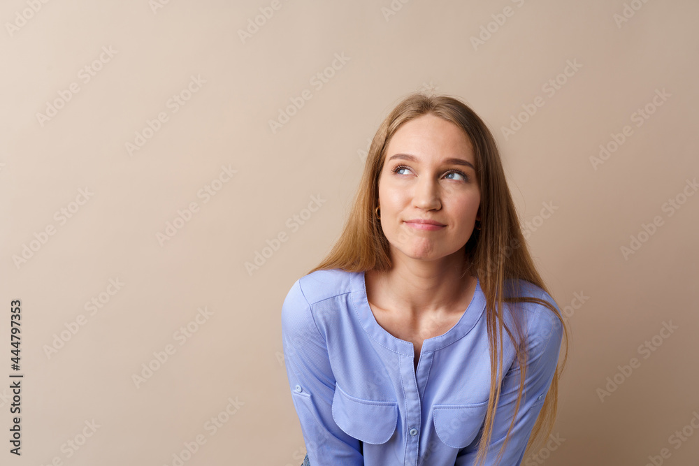 Pensive young businesswoman thinking about some idea against beige background Pensive young businesswoman thinking about some idea against beige background