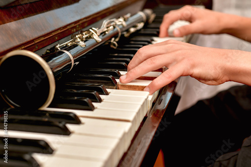 The pianist plays the white piano keys, the clarinet lies nearby.