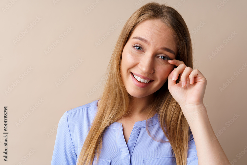 Emotional young woman heard a joke laughing to tears against beige background Emotional young woman heard a joke laughing to tears against beige background