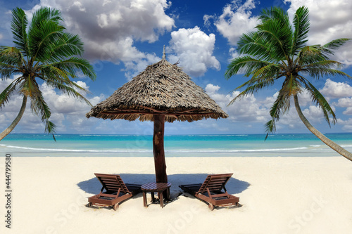 Beautiful tropical beach witn straw umbrella and palm