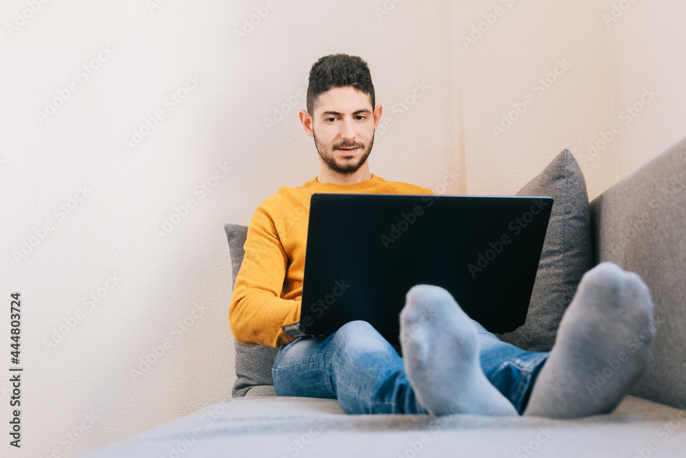 Mid adult man working remotely from the sofa at home. Concept of future, family balance and home workspace. Mid adult man working remotely from the sofa at home. Concept of future, family balance and home workspace.