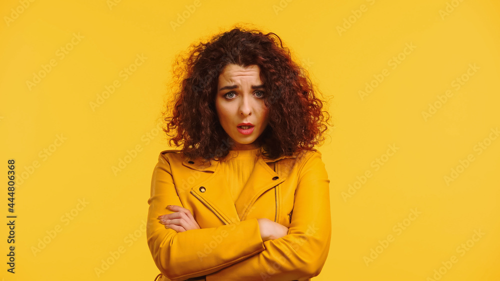 offended woman in leather jacket standing with crossed arms isolated on yellow offended woman in leather jacket standing with crossed arms isolated on yellow