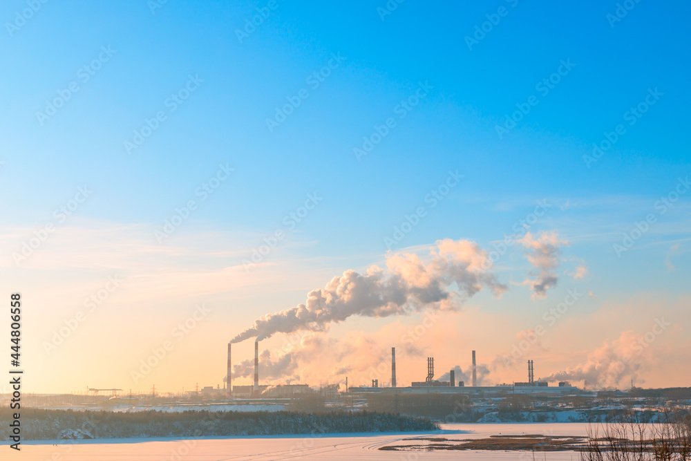 a clear winter day and a steaming plant by a frozen river