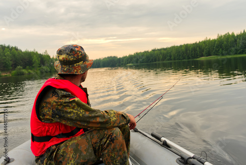 Foto A fisherman on an inflatable boat catches fish on spinning