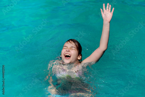 The girl drowns in water and raises her hand up calling for help. The girl drowns and screams.