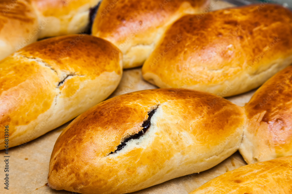 Baked buns stuffed with currant jam on parchment paper. Baked buns stuffed with currant jam on parchment paper.