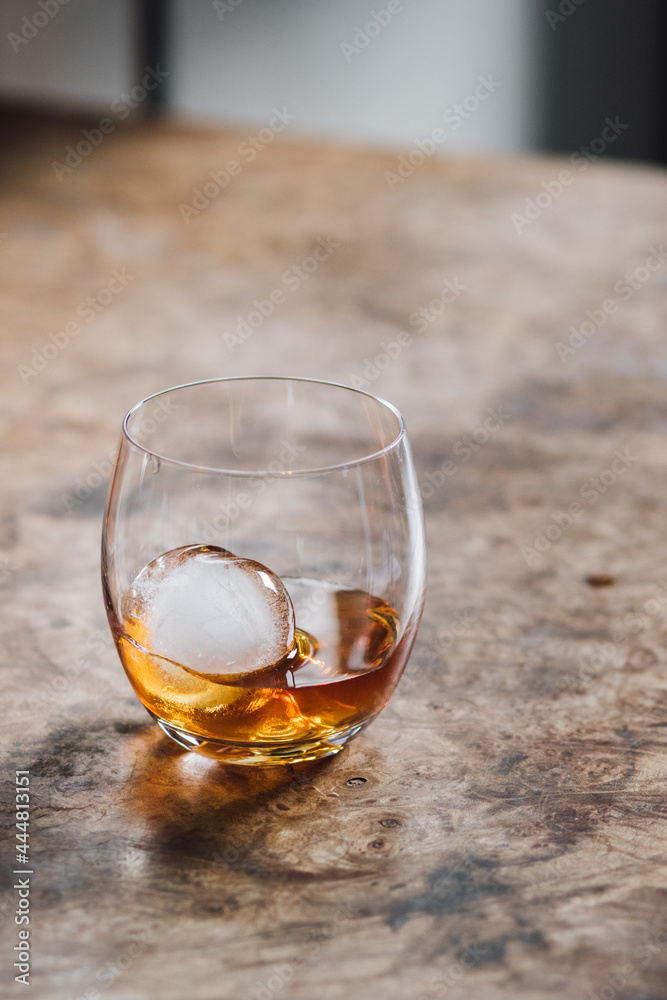 glass dram of whiskey whisky with sphere ice on wood table glass dram of whiskey whisky with sphere ice on wood table