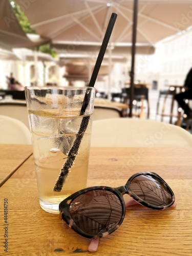 It's summer it's hot, close-up at a cafe terrace table, on a glass, sparkling water and a pair of sunglasses