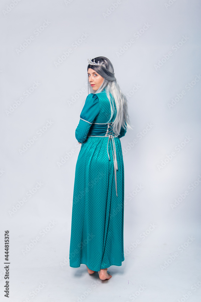 Full length portrait of a standing back princess in a medieval, fantasy, turquoise dress with ash hair and a silver crown posing isolated on a white background. Full length portrait of a standing back princess in a medieval, fantasy, turquoise dress with ash hair and a silver crown posing isolated on a white background.