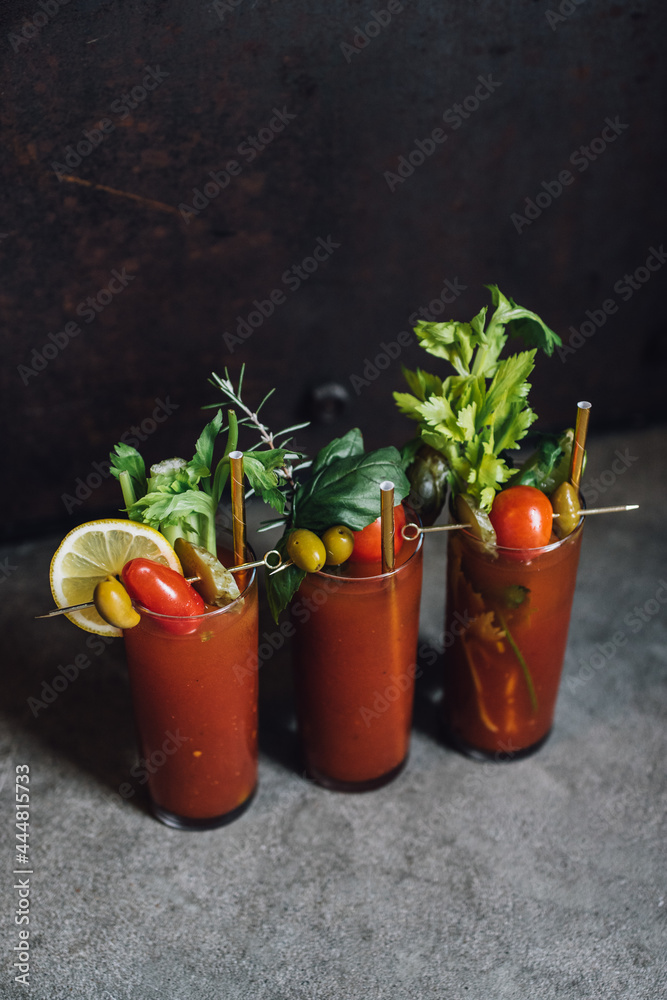 set of three Bloody Mary tomato brunch cocktail drink with celery, lemon, rosemary, pickles, olives garnish with gold straw in tall glass set of three Bloody Mary tomato brunch cocktail drink with celery, lemon, rosemary, pickles, olives garnish with gold straw in tall glass